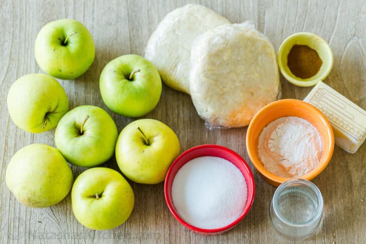 Crust for pie with ingredients to make pie including apples, sugar, flour, butter, cinnamon