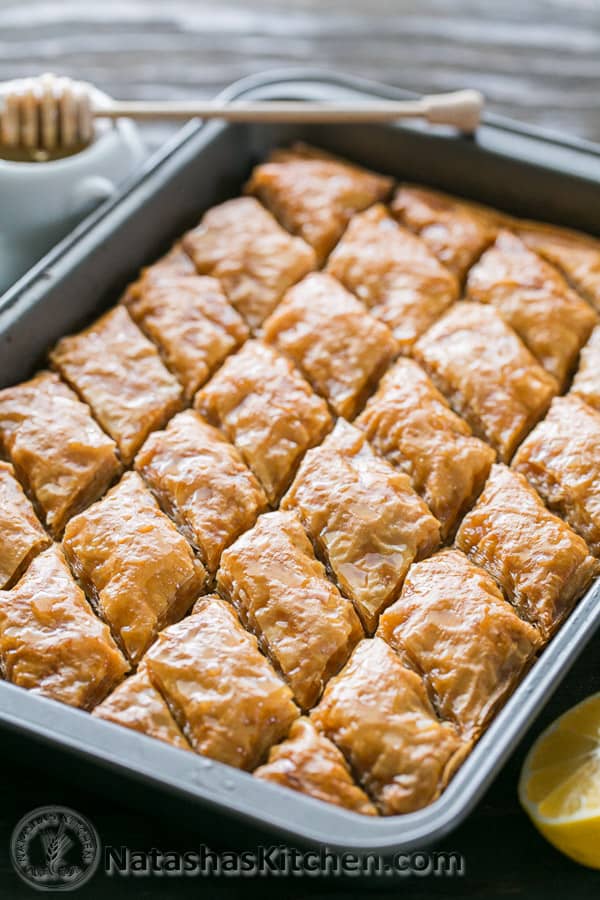 Homemade baklava displayed sliced in baking sheet drizzled with hot honey lemon syrup for the best baklava recipe