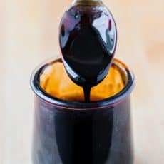 Balsamic glaze pouring off a spoon into jar
