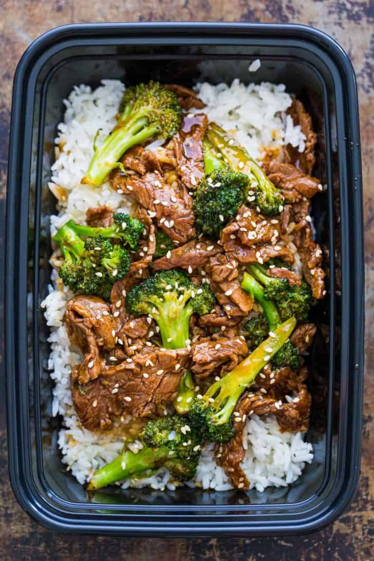 Meal prepped broccoli beef served over white rice in to-go box or thermos
