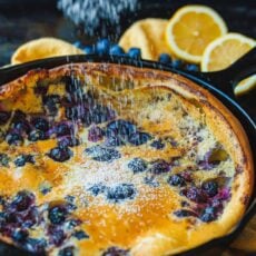 blueberry lemon dutch baby in skillet with powdered sugar sprinkled on top