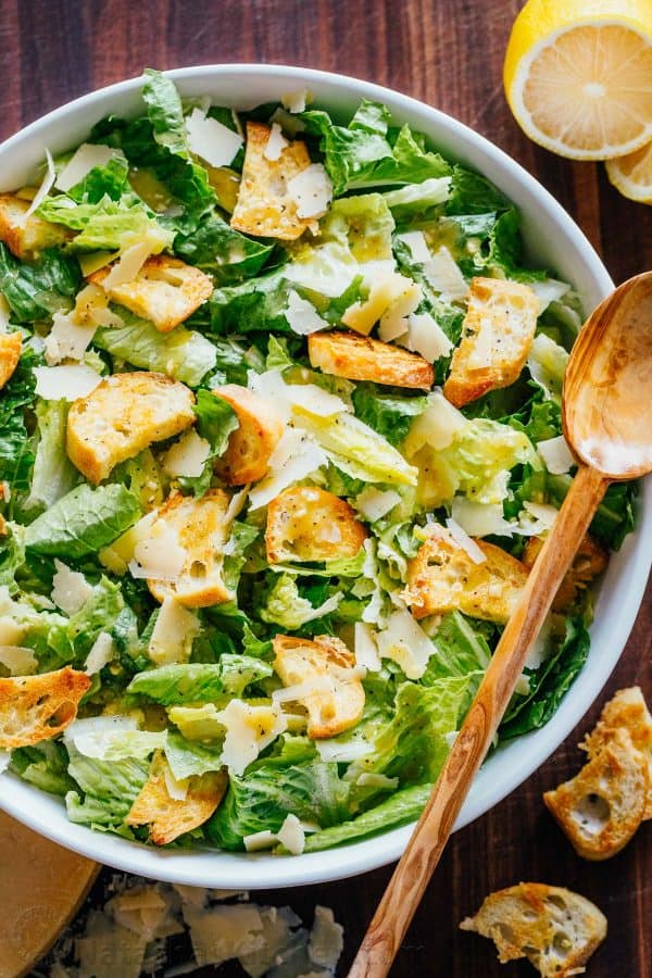 Classic Caesar Salad in a bowl with homemade croutons, shaved parmesan and caesar salad dressing