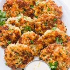 Cheesy Shrimp Cakes aka Shrimp Fritters with irresistible lemon aioli sauce. One of our favorite shrimp recipes! Biting into juicy shrimp, fritter style, is a real treat. The cheese creates an irresistible cheese pull inside and forms a golden crust on the outside. Watch the Video tutorial and you will just know; this recipe is GOOD | natashaskitchen.com