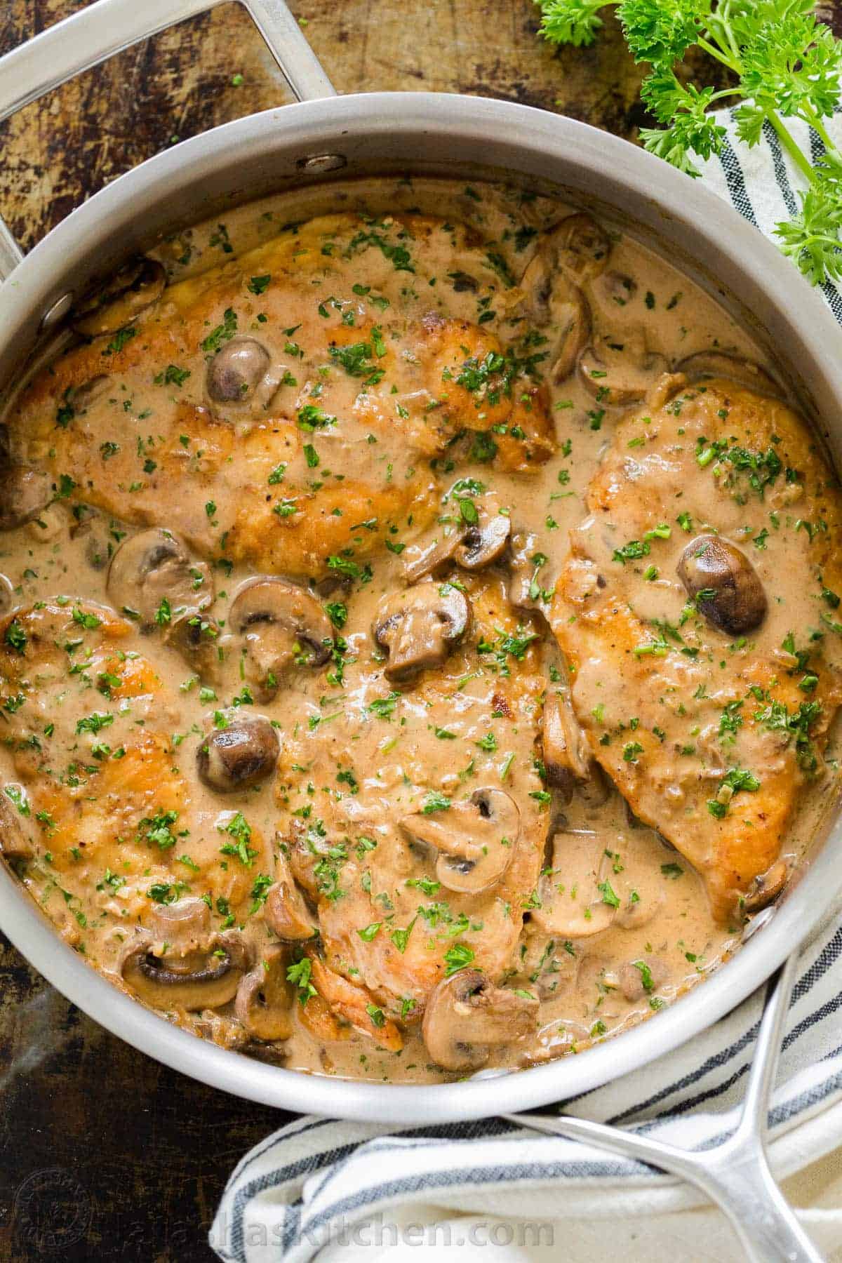 Chicken Marsala topped with parsley and mushrooms in a pan.