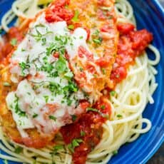 chicken Parmesan served over spaghetti and marinara sauce garnished with basil and parsley