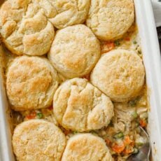 Overhead view of a spoon scooping a serving of chicken pot pie casserole from a baking dish.