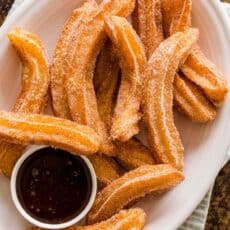 Churros on a serving platter with a bowl of chocolate sauce