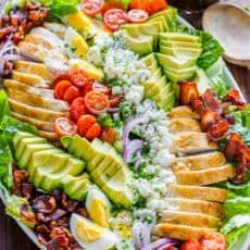 Chicken Cobb Salad on a platter with salad dressing in a mason jar