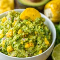 Grilled corn guacamole in a bowl with a tortilla chip