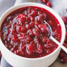 A bowl of homemade cranberry sauce with a spoon.