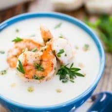 A blue bowl of creamy cauliflower and potato soup with shrimp
