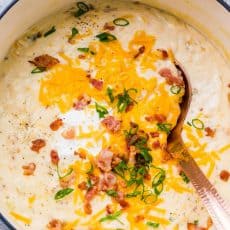 Potato Soup garnished with cheese, chives, bacon and sour cream in a pot
