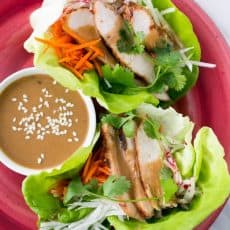 A red plate with Terah's delicious lettuce wraps with a little bowl of sauce beside them