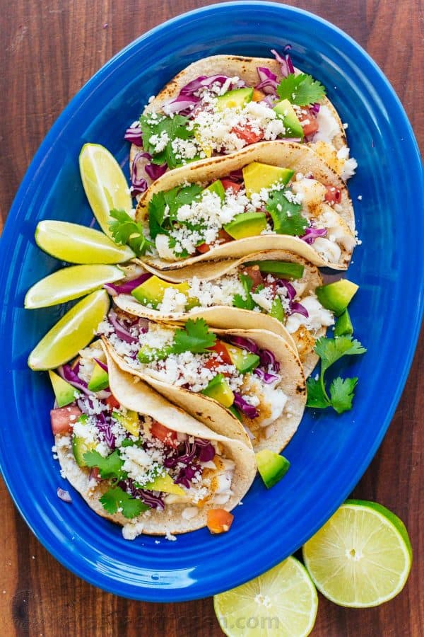 Our go-to fish tacos recipe for entertaining! Easy, excellent fish tacos with the best fish taco sauce; an irresistible lime crema! | natashaskitchen.com