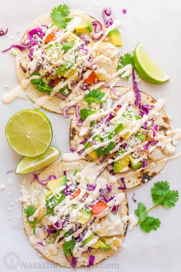 Our go-to fish tacos recipe for entertaining! Easy, excellent fish tacos with the best fish taco sauce; an irresistible lime crema! | natashaskitchen.com