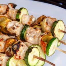 Grilled garlic chicken skewers on a white plate