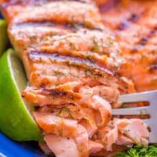 Grilled salmon on a blue plate flaked with a fork