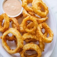 Onion rings on plate with small bowl of dipping sauce