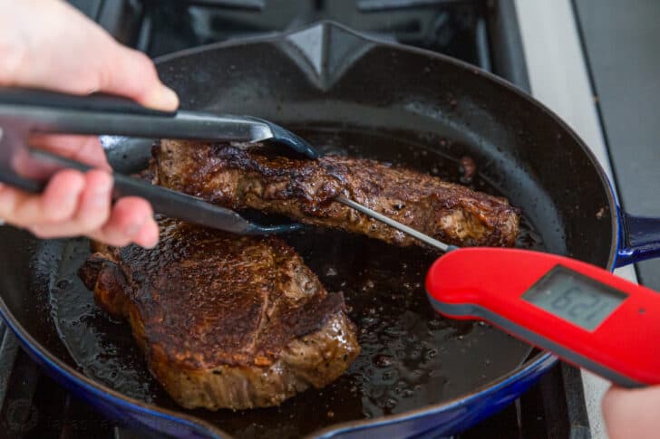 Checking steak temperature inserting thermometer into side of steak