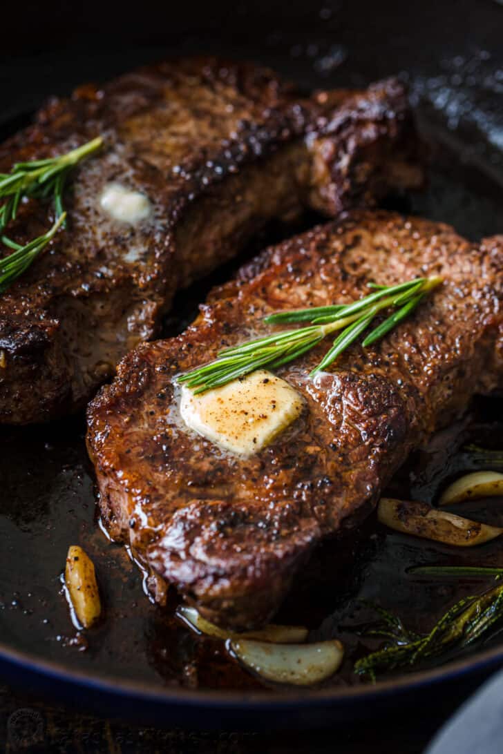Juicy steak on a pan topped with garlic rosemary butter