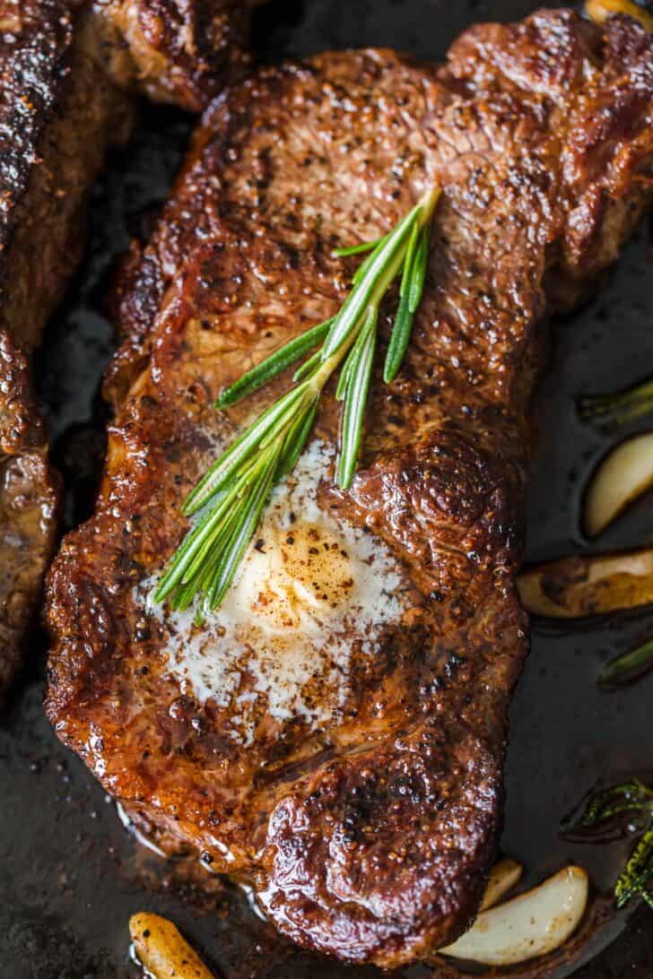 Juicy steak topped with melted garlic butter and rosemary