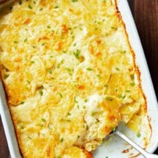 Golden baked au gratin potatoes in a rectangular baking dish with a scoop missing.