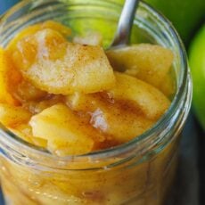 Close up of a mason jar filled with sauteed cinnamon apples with a spoon.
