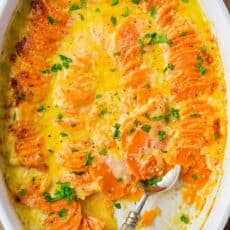 Scalloped Sweet Potatoes in casserole dish with serving spoon
