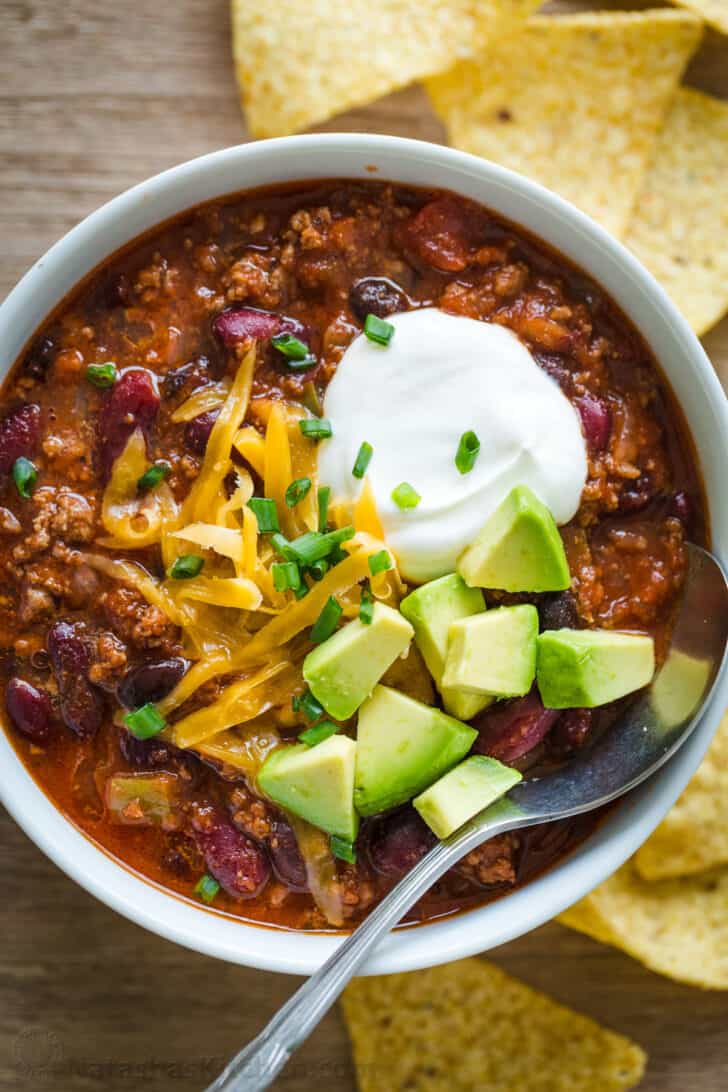 Slow Cooker chili served in a bowl garnished with cheese, sour cream and avocado