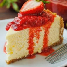 strawberry cheesecake sliced on a plate with strawberry sauce topping