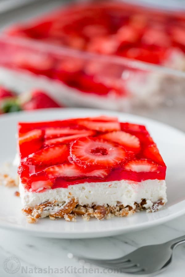 Slice of strawberry pretzel salad served on a plate with layers of pretzels, cream and strawberry strawberry jello dessert 