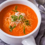 Creamy tomato soup garnished with cheese and basil