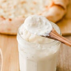 White pizza sauce on a spoon and in mason jar